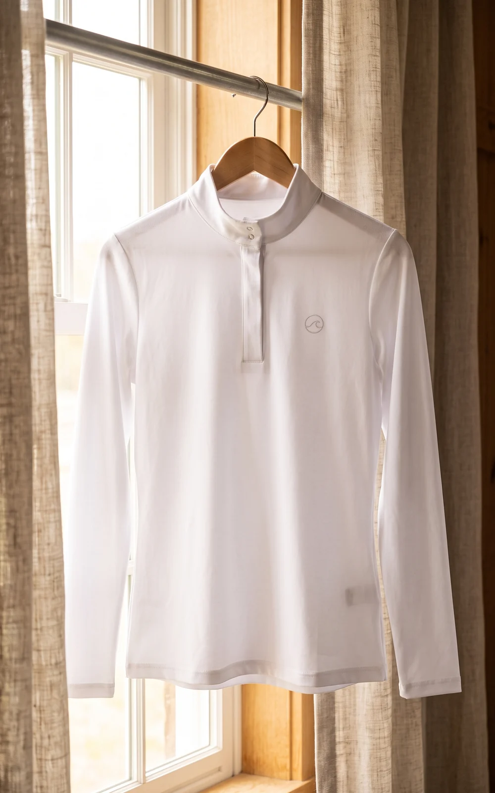 Camisa de concurso blanca colgada junto a una ventana