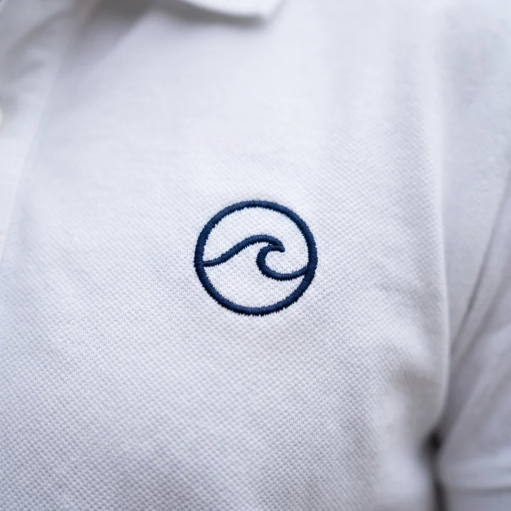 Logo bordado en el pecho de un polo blanco