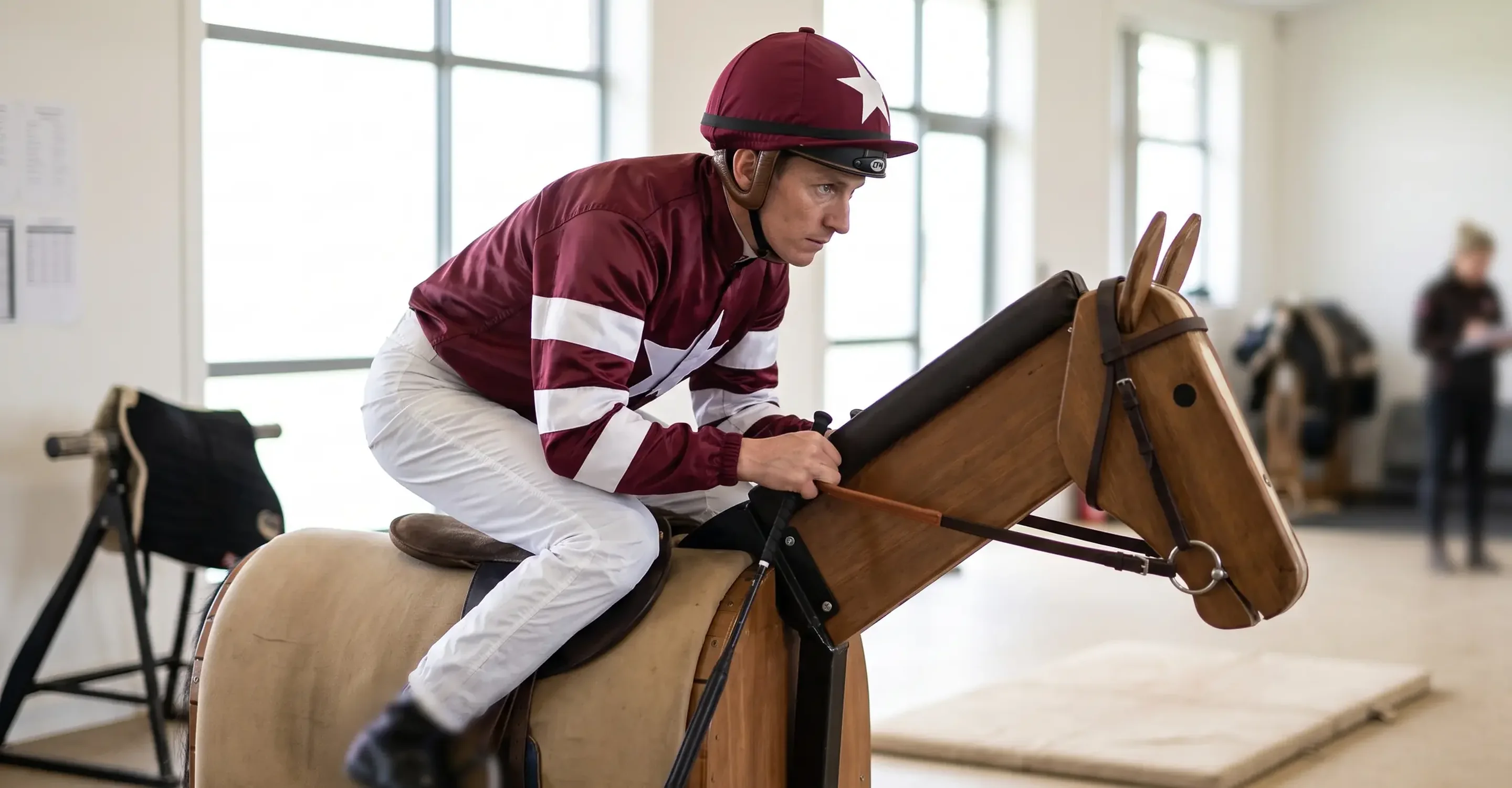 Jockey probando la muestra granate en postura de carrera sobre el simulador